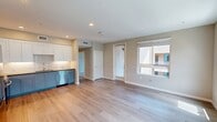 This thoughtfully designed 610-square-foot, one-bedroom, one-bathroom apartment at North Grove (Unit 21-302) in Riverside, CA offers a clean, modern aesthetic across a single floor. The open-concept kitchen and living area serves as the heart of the unit, featuring light hardwood-style flooring, recessed lighting, and large windows fitted with blinds that allow generous natural light to fill the space. The kitchen is well-appointed with two-tone cabinetry — white upper cabinets and slate-blue lower cabinets — complemented by a subway tile backsplash, dark countertops, and a full suite of stainless steel appliances including a refrigerator, range, microwave, and dishwasher. The living room offers views of the surrounding community through multiple windows, with access to an outdoor balcony overlooking the streetscape and palm tree-lined surroundings. The 120-square-foot bedroom features plush carpet flooring and a large window providing natural light and exterior views. A dedicated walk-in closet with wire shelving provides ample storage. The bathroom includes light wood-style flooring, a vanity with blue-gray cabinetry, a large mirror, and a tiled shower-tub combo. A hallway connects all rooms efficiently, completing this well-organized, contemporary living space.