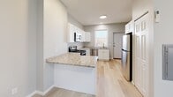 Located at 33-35 Rowe Ave in Hartford, CT, this single-floor, 3-bedroom, 2-bathroom unit offers a thoughtfully designed layout that maximizes functionality within a compact footprint. Light-toned hardwood flooring runs throughout the living areas and bedrooms, creating a cohesive, bright aesthetic complemented by neutral gray walls.

The kitchen serves as a central feature, equipped with white shaker cabinets, granite countertops, stainless steel appliances including a refrigerator, range, microwave, and dishwasher, and a peninsula that provides additional prep and storage space. Recessed lighting and a window contribute to a well-lit, practical cooking environment.

Each bedroom is finished with the same light hardwood flooring and neutral tones. Multiple bedrooms feature wall-mounted mini-split HVAC units for individualized climate control, and windows allow natural light to filter in. The primary bedroom offers a comfortable, functional space with a sliding door.

The two bathrooms each feature walk-in showers with tiled surrounds—one showcasing a marble-style tile with dark accent banding, the other with warm beige tiling and a mosaic pebble shower floor. Both bathrooms include white vanities and coordinating tile flooring, presenting a clean, updated appearance throughout.