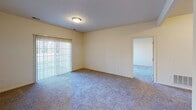 This single-floor residence at 1913 University Park Dr in Westville, Indiana offers a well-organized layout designed for comfortable everyday living. The spacious living area is finished with plush wall-to-wall carpeting and features a large sliding glass door fitted with vertical blinds, allowing natural light to fill the room while providing access to outdoor views. A welcoming entry hallway connects the main living spaces and leads seamlessly through the home. The kitchen is thoughtfully equipped with warm honey-toned wood cabinetry, ample counter space, a double stainless steel sink, a gas range, and a built-in microwave, all set atop easy-care hardwood-style flooring. A pass-through window connects the kitchen to the adjacent living area, enhancing the open feel of the space. The bedrooms are carpeted and well-lit, with ceiling fans and generous windows that bring in natural light and exterior views of the surrounding community. The bathrooms are finished with neutral tile flooring and include a full bathtub and shower combination with a curtain rod, a wood-toned vanity, and clean, functional fixtures throughout. The overall aesthetic is warm and neutral, with cream-toned walls and consistent finishes creating a cohesive and inviting atmosphere throughout the home.