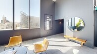 The Skylounge at 1737 N Las Palmas Ave in Hollywood, Los Angeles, is a sophisticated, single-floor amenity space designed with a refined modern aesthetic. The open layout is anchored by soaring ceilings and expansive floor-to-ceiling windows that flood the interior with natural light and frame sweeping panoramic views of the Hollywood skyline. Large-format tile flooring runs throughout, lending a clean, cohesive feel to the space.

The main lounge area features a curated selection of contemporary seating, including tan leather accent chairs and glass-topped tables, complemented by lush indoor plants that add a natural, calming element. A corner seating nook, fully enclosed by oversized windows, offers an intimate setting with unobstructed city views on multiple sides.

The kitchenette area is a standout feature, finished with warm light wood cabinetry, a marble-style countertop island with bar seating, and an open display shelf adorned with artful ceramic vessels. A matte black sink and integrated appliances complete the functional yet elegant workspace.

A restroom is included in the space, designed in a contemporary style with deep charcoal walls, a wall-mounted white basin, a round mirror with linear LED lighting, and accessible fixtures. Curated artwork and thoughtful decorative touches are present throughout, reinforcing the elevated, design-forward character of this Hollywood lounge.