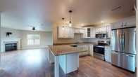 Located at 115 Silver Lake Plaza in Oconomowoc, Wisconsin, this single-floor home offers a well-designed open layout that seamlessly connects the kitchen, dining, and living areas. The kitchen is a standout feature, showcasing crisp white raised-panel cabinetry with glass-front accents, granite countertops, a central peninsula with pendant lighting, and a full suite of stainless steel appliances including a range, microwave, dishwasher, and refrigerator. Durable hardwood-style flooring flows throughout the main living spaces, adding warmth and continuity to the design. The spacious living room is anchored by a classic stone-surround fireplace and ceiling fan, with a window providing natural light and a sliding glass door offering direct outdoor access. Additional bedrooms feature the same hardwood-style flooring or plush carpeting, with large windows that invite abundant natural light. The bathrooms are finished with matching granite-top vanities, warm wood cabinetry, large mirrors, and wood-look flooring, maintaining a cohesive aesthetic throughout. Neutral wall tones and clean white trim create a bright, move-in-ready atmosphere that suits a variety of interior styles throughout this thoughtfully designed home.