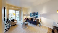 This single-floor residence is thoughtfully designed with a cohesive, contemporary aesthetic throughout. The kitchen is equipped with stainless steel appliances, including a range, microwave, and refrigerator, complemented by dark espresso cabinetry and a light marble-style countertop island. Wood-style flooring anchors the kitchen and entry area, adding warmth and durability.

The living room is generously sized with soft wall-to-wall carpeting, neutral warm-toned walls, and a large sliding glass door that floods the space with natural light and provides access to an outdoor view. The open layout comfortably accommodates a full seating arrangement.

Both bedrooms feature plush carpeting, large windows with outdoor views, and ample wall space. One bedroom includes access to a spacious walk-in closet outfitted with wire shelving on multiple walls, offering substantial storage capacity.

The full bathroom is well-appointed with a double-sink vanity featuring a granite countertop, dark cabinetry, a large framed mirror, a soaking tub with shower, and a stacked washer and dryer unit conveniently integrated into the space. Tile flooring completes the clean, functional design.