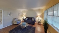 This single-floor home in Sherman offers a comfortable and functional layout spread across several well-appointed rooms. The living room serves as the heart of the home, featuring warm hardwood-style flooring, neutral-toned walls, and a large multi-pane window that floods the space with natural light. Crown molding adds a clean, finished touch to the room's upper edges.

The kitchen is efficiently designed with rich dark cabinetry, light countertops, a black range, and a single-basin sink. A window above the counter brings in additional natural light, making the space feel open and practical for everyday cooking.

Adjacent to the kitchen, the dining area provides an intimate setting with ceiling fan lighting overhead, offering a cozy spot for meals and gatherings.

The home includes multiple bedrooms, each equipped with ceiling fans, hardwood-style flooring, and windows with window treatments. The primary bedroom offers ample space and wall-mount TV capability, while a secondary bedroom presents a versatile layout.

The bathroom features a tub-shower combination with a decorative curtain, hardwood-style flooring, and a spacious vanity area with a wide mirror and Hollywood-style lighting, along with a convenient linen closet nearby.

Throughout the home, consistent flooring, neutral warm tones, and practical fixtures create a cohesive and inviting atmosphere.