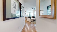 This well-designed single-floor residence offers a cohesive blend of modern finishes and comfortable living spaces. A welcoming hallway adorned with framed artwork leads into the open-concept living and dining area, where large windows flood the space with natural light. The living room features warm hardwood flooring, a ceiling fan, and generous seating space, while the adjacent dining nook — surrounded by windows on multiple sides — provides an airy spot for meals.

The kitchen is a standout feature, outfitted with crisp white shaker cabinetry, classic subway tile backsplash, quartz countertops, and a full suite of stainless steel appliances including a gas range, dishwasher, over-the-range microwave, and a French door refrigerator. A peninsula provides additional counter space and casual seating.

The bedrooms are comfortably sized, each featuring hardwood floors, large windows with views of the surrounding neighborhood, and soft accent wall colors in muted sage green tones. The primary bathroom includes a dual-sink vanity with quartz countertops, white cabinetry, matte black hardware, and a subway-tiled shower. A secondary bathroom features a full soaking tub with subway tile surround and built-in shelving for added storage. Hardwood flooring flows consistently throughout the entire residence.