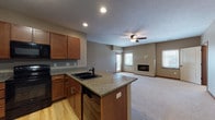 This single-floor residence offers a thoughtfully designed layout that balances comfort and functionality. The open-concept kitchen and living area serves as the heart of the home, where light hardwood flooring in the kitchen transitions seamlessly into plush carpeting in the living room. The kitchen is outfitted with warm medium-toned wood cabinetry, granite countertops, a peninsula with a double basin sink, and a full suite of black appliances including a refrigerator with ice maker, electric range, and built-in microwave. The spacious living room features a ceiling fan, a built-in fireplace, and multiple windows that invite natural light throughout the space. The bedrooms are carpeted and well-sized, each benefiting from natural light via window treatments. The unit includes two bathrooms — one with a walk-in shower featuring built-in shelving and a glass block window, and another with a full soaking tub and shower combination. Both bathrooms are finished with large-format tile flooring and granite-topped vanities with matching wood cabinetry. Storage is plentiful, with multiple walk-in closets equipped with wire shelving systems. A dedicated in-unit laundry room accommodates a full-sized washer and dryer with additional wire shelving for storage.