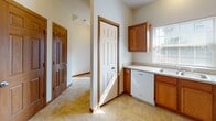 Located at 2704 Westmar Ct in Toledo, Ohio, this two-story home offers a practical and comfortable layout spread across two levels connected by a wood-railed staircase. The main level features a combined dining and living area, where plush carpeting and a pendant chandelier create a welcoming atmosphere. A sliding glass door in the living area fills the space with natural light and provides direct access to the outdoors. The kitchen is well-appointed with warm oak cabinetry, ample counter space, a double-basin sink, a dishwasher, and tile flooring, with a window above the sink offering additional natural light. The upper level hosts multiple carpeted bedrooms, each equipped with ceiling fans and windows dressed with blinds. The bedrooms are generously sized, with six-panel wood doors and wood trim detailing throughout. Bathrooms are finished with oak vanities topped with solid countertops, large mirrors, and tile flooring. One bathroom includes a tub and shower combination. Consistent wood trim, neutral wall tones, and carpeted living spaces tie the home together with a cohesive, classic aesthetic throughout both floors.