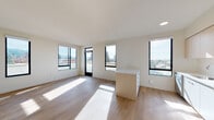 Located at 2530 Shattuck Ave in Berkeley, CA, this modern single-floor unit offers a bright, contemporary living experience with clean lines and a neutral palette throughout. The open-concept living and dining area is bathed in natural light, courtesy of expansive black-framed windows that frame sweeping views of the Berkeley Hills and surrounding cityscape. Light wood flooring flows seamlessly throughout the space, enhancing its airy ambiance.

The kitchen is well-appointed with two-tone cabinetry — combining white lower cabinets with light wood upper cabinets — a white tile backsplash, quartz countertops, a central island with integrated storage, and a full suite of stainless steel appliances including a range, over-the-range microwave, dishwasher, and refrigerator. Recessed lighting completes the functional yet stylish design.

The bedrooms are generously proportioned, featuring large windows, light wood flooring, wall-mounted mini-split HVAC units, and built-in closets. The bathroom is finished in a clean, minimalist style with a white vanity, quartz countertop, mirrored medicine cabinet, and a tiled soaking tub with shower combo. The overall design aesthetic is consistently modern and move-in ready.