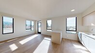 Located at 2530 Shattuck Ave in Berkeley, CA, this modern single-floor unit offers a bright, contemporary living experience with clean lines and a neutral palette throughout. The open-concept living and dining area is bathed in natural light, courtesy of expansive black-framed windows that frame sweeping views of the Berkeley Hills and surrounding cityscape. Light wood flooring flows seamlessly throughout the space, enhancing its airy ambiance.

The kitchen is well-appointed with two-tone cabinetry — combining white lower cabinets with light wood upper cabinets — a white tile backsplash, quartz countertops, a central island with integrated storage, and a full suite of stainless steel appliances including a range, over-the-range microwave, dishwasher, and refrigerator. Recessed lighting completes the functional yet stylish design.

The bedrooms are generously proportioned, featuring large windows, light wood flooring, wall-mounted mini-split HVAC units, and built-in closets. The bathroom is finished in a clean, minimalist style with a white vanity, quartz countertop, mirrored medicine cabinet, and a tiled soaking tub with shower combo. The overall design aesthetic is consistently modern and move-in ready.