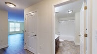 Located at 211 W Mulberry St in Baltimore, MD, this two-bedroom, two-bathroom residence offers a practical and well-appointed single-floor layout. The open-concept kitchen and living area serves as the heart of the home, featuring rich dark-espresso cabinetry, granite-style countertops, a peninsula with a double sink, and black appliances including a range, microwave, dishwasher, and refrigerator. Light wood-style flooring runs throughout the main living areas, creating a cohesive and clean aesthetic. The primary bedroom is a comfortable retreat, finished with plush carpeting, a ceiling fan, and a window that allows natural light to filter in. The second bedroom also features carpeted floors, its own window, and a dedicated closet with a rod for hanging storage. Both bathrooms are finished consistently, each offering a full tub-and-shower combo with white tile surround, a dark-toned vanity, and stone-look tile flooring. Three closets throughout the unit provide ample storage. A dedicated laundry area and a connecting hallway round out the functional layout. The unit's neutral color palette and clean finishes offer a move-in-ready feel in the heart of Baltimore.
