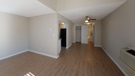 This renovated upstairs unit offers a thoughtfully designed single-floor layout with 1 bedroom and 1 bathroom. The living area is bright and open, featuring wood-look plank flooring, vaulted ceiling details, and a ceiling fan. A sliding glass door floods the space with natural light and opens to a private balcony, providing elevated outdoor views. A wall-mounted air conditioning unit ensures year-round comfort.

The kitchen has been updated with white shaker cabinetry, gray countertops, and a full suite of stainless steel appliances, including a range, microwave, dishwasher, and refrigerator. A window above the sink brings in additional natural light.

The hallway connects the living area to the bedroom and bathroom, with a closet providing convenient storage. The bedroom features neutral carpet, a window with blinds, and a textured ceiling. The bathroom is finished with a white vanity, gray countertop, modern light fixtures, a large mirror, and wood-look flooring that complements the rest of the unit. Warm, neutral tones throughout create a cohesive and move-in-ready atmosphere.