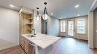 Located at 2080 FM 1102 in New Braunfels, TX, this thoughtfully designed one-bedroom, one-bathroom unit offers a clean, modern aesthetic throughout its single floor. The kitchen is a standout feature, showcasing warm wood cabinetry, a striking quartz waterfall-edge island with an undermount sink, and a full suite of stainless steel appliances including a side-by-side refrigerator with ice maker, electric range, and microwave. Pendant lighting over the island adds a polished finishing touch. Luxury vinyl plank flooring runs throughout the main living areas and bedroom, providing a cohesive and low-maintenance surface. The bedroom is a comfortable, well-proportioned retreat with soft neutral walls, natural light from dual windows, and a ceiling fan for year-round comfort. The bathroom is elegantly appointed with a double-sink vanity featuring warm wood cabinetry, backlit mirrors, and matte black hardware. A glass-enclosed walk-in shower with full marble-style tile adds a spa-like quality to the space. A dedicated laundry area houses a full-size Whirlpool washer and dryer with built-in shelving above for added storage. A closet and two hallways complete the functional, well-organized layout of this contemporary home.