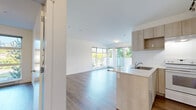 Located at 1408 E 15th Ave in Vancouver's vibrant East Side, this 2-bedroom, 1-bathroom unit offers a well-designed, single-floor layout with a clean, modern aesthetic throughout. Hardwood-style flooring runs continuously across the space, complemented by crisp white walls that enhance the sense of brightness and openness.

The open-concept kitchen and living area serves as the heart of the unit. The kitchen features light wood cabinetry, white quartz countertops, a subway tile backsplash, track lighting, and a peninsula with an integrated sink — ideal for both cooking and entertaining. The living area is bathed in natural light through expansive floor-to-ceiling windows that frame lush greenery and neighborhood views, with direct access to a private balcony.

A well-proportioned hallway connects the living spaces to two bedrooms, each featuring hardwood-style flooring and windows that invite natural light. Both bedrooms are served by closets, providing practical built-in storage with clean bi-fold doors. The primary bedroom offers a comfortable footprint suited for a full bedroom setup.

The bathroom is finished with clean white tile surrounding a full soaker tub. A dedicated laundry area adds everyday convenience, completing this efficiently designed and well-appointed urban home.