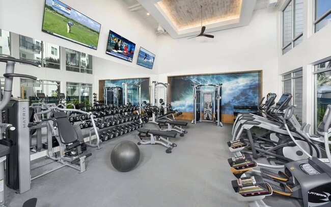Tres pantallas y una pared decorada con motivos de surf evitan que la sala de pesas parezca sosa. - Anchor Riverwalk