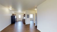 Located at 5629 Elysian Road in Billings, Montana, this single-story space offers a clean, functional layout designed for comfortable everyday living. The interior is characterized by rich, dark hardwood-style flooring that runs throughout the main living areas, creating a warm and cohesive aesthetic against the bright white walls and smooth ceilings.

The open layout connects the main living area to the kitchen, which is equipped with dark cabinetry, a refrigerator, and a range. A utility panel is conveniently housed within the space, and multiple windows allow natural light to filter in, brightening the interior and enhancing the sense of openness.

The layout includes multiple doorways leading to additional rooms, suggesting a practical and well-organized floor plan. The smooth, light-colored ceilings paired with flush-mount lighting fixtures provide ample illumination throughout. The overall ambiance is clean and neutral, offering a move-in-ready canvas that lends itself well to a variety of interior styles and furnishing preferences.