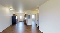 Located at 5629 Elysian Road in Billings, Montana, this single-story space offers a clean, functional layout designed for comfortable everyday living. The interior is characterized by rich, dark hardwood-style flooring that runs throughout the main living areas, creating a warm and cohesive aesthetic against the bright white walls and smooth ceilings.

The open layout connects the main living area to the kitchen, which is equipped with dark cabinetry, a refrigerator, and a range. A utility panel is conveniently housed within the space, and multiple windows allow natural light to filter in, brightening the interior and enhancing the sense of openness.

The layout includes multiple doorways leading to additional rooms, suggesting a practical and well-organized floor plan. The smooth, light-colored ceilings paired with flush-mount lighting fixtures provide ample illumination throughout. The overall ambiance is clean and neutral, offering a move-in-ready canvas that lends itself well to a variety of interior styles and furnishing preferences.