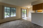 Located at 450 N Soldano Ave in Azusa, California, this single-floor residence offers a well-organized layout designed for comfortable everyday living. The living area is generously proportioned, featuring wall-to-wall carpeting, a ceiling fan with light fixture, a textured ceiling, and abundant natural light drawn in through large multi-pane windows. A sliding glass door opens directly to a private balcony, extending the living space outdoors with views of surrounding greenery. A half-wall with overhead cabinetry separates the living area from the galley-style kitchen, which is equipped with warm wood-toned cabinetry, light countertops, a double-basin sink, a dishwasher, an electric range with overhead ventilation, and tile flooring beneath a panel light ceiling. The bedrooms are carpeted and well-lit by multi-pane windows, offering quiet and comfortable retreats. The bathroom features tile flooring, a vanity with an integrated sink, a medicine cabinet mirror, and access to a hallway that connects the private areas of the home. Throughout the space, neutral wall tones and consistent finishes create a cohesive and functional living environment.