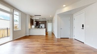 This single-floor residence features a thoughtfully designed open-concept layout that seamlessly connects the living area to the kitchen. Warm-toned hardwood flooring extends throughout the main living spaces, creating a cohesive and inviting atmosphere. The entry foyer leads directly into the spacious living area, which benefits from a clean, minimalist aesthetic with crisp white walls and recessed lighting overhead.

The kitchen is a standout feature, outfitted with rich dark wood cabinetry, light granite countertops, and a classic white subway tile backsplash. A peninsula with pendant lighting provides additional prep space and casual seating. Stainless steel appliances — including a French door refrigerator, electric range, dishwasher, and microwave — complete the modern setup. A window above the sink allows natural light to fill the space.

The bedroom is carpeted for comfort and features a large window that brings in natural light, along with a generously sized walk-in closet equipped with shelving and hanging storage. The full bathroom offers a tiled tub-surround, granite vanity countertop, warm wood cabinetry, and large-format floor tiles, delivering a clean, contemporary finish throughout.