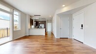 This single-floor residence features a thoughtfully designed open-concept layout that seamlessly connects the living area to the kitchen. Warm-toned hardwood flooring extends throughout the main living spaces, creating a cohesive and inviting atmosphere. The entry foyer leads directly into the spacious living area, which benefits from a clean, minimalist aesthetic with crisp white walls and recessed lighting overhead.

The kitchen is a standout feature, outfitted with rich dark wood cabinetry, light granite countertops, and a classic white subway tile backsplash. A peninsula with pendant lighting provides additional prep space and casual seating. Stainless steel appliances — including a French door refrigerator, electric range, dishwasher, and microwave — complete the modern setup. A window above the sink allows natural light to fill the space.

The bedroom is carpeted for comfort and features a large window that brings in natural light, along with a generously sized walk-in closet equipped with shelving and hanging storage. The full bathroom offers a tiled tub-surround, granite vanity countertop, warm wood cabinetry, and large-format floor tiles, delivering a clean, contemporary finish throughout.
