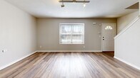 This two-story unit at 1301-1345 NE 39th St in Kansas City, Missouri, offers a functional and well-organized layout spread across two floors. The main level houses the kitchen and living room, both finished with wood-look luxury vinyl plank flooring that continues throughout the home. The living room features track lighting and a front entry door flanked by a window that admits natural light. The kitchen is equipped with stainless steel appliances, including a refrigerator, range, microwave, and dishwasher, complemented by warm-toned wood cabinetry, light countertops, and a chandelier overhead. A half bathroom on the main level adds convenience.

The upper floor contains both bedrooms and two additional bathrooms. The primary bedroom is a well-proportioned space featuring a ceiling fan with light fixture. The second bedroom also includes a ceiling fan, a closet, and natural light from a window. One of the upper-level bathrooms features warm wood cabinetry with a vanity sink, while another presents a clean, minimalist design with white finishes. Throughout the unit, light-toned vinyl plank flooring, neutral wall colors, and consistent trim details create a cohesive and modern aesthetic.