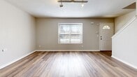 This two-story unit at 1301-1345 NE 39th St in Kansas City, Missouri, offers a functional and well-organized layout spread across two floors. The main level houses the kitchen and living room, both finished with wood-look luxury vinyl plank flooring that continues throughout the home. The living room features track lighting and a front entry door flanked by a window that admits natural light. The kitchen is equipped with stainless steel appliances, including a refrigerator, range, microwave, and dishwasher, complemented by warm-toned wood cabinetry, light countertops, and a chandelier overhead. A half bathroom on the main level adds convenience.

The upper floor contains both bedrooms and two additional bathrooms. The primary bedroom is a well-proportioned space featuring a ceiling fan with light fixture. The second bedroom also includes a ceiling fan, a closet, and natural light from a window. One of the upper-level bathrooms features warm wood cabinetry with a vanity sink, while another presents a clean, minimalist design with white finishes. Throughout the unit, light-toned vinyl plank flooring, neutral wall colors, and consistent trim details create a cohesive and modern aesthetic.