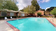 Located at 2414 Stone Rd in East Point, Georgia, this single-story property is defined by its classic brick construction and well-maintained outdoor amenities. The exterior showcases traditional brick masonry complemented by large windows that allow natural light to reach the interior spaces. The standout feature of this property is its generously sized outdoor swimming pool, which is framed by brick-trimmed edges and a wide concrete deck. The pool area is thoughtfully appointed with multiple lounge chairs, providing ample space for relaxation and recreation. Lush, mature trees surround the perimeter, offering natural shade and a sense of privacy, while neatly trimmed hedges and potted greenery add to the landscaping detail. A black iron perimeter fence encloses the outdoor area, contributing both aesthetic definition and security to the space. The combination of classic brick architecture, open poolside layout, and verdant natural surroundings creates an inviting and functional outdoor environment. The property's single-floor design ensures easy accessibility throughout, making it a practical and attractive space well-suited for community or residential use in the East Point area.
