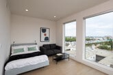 Located on the seventh floor at 1775 Beloit Ave in the vibrant West Los Angeles neighborhood of 90025, Unit 704 is a thoughtfully designed modern residence that combines clean aesthetics with functional living. Light hardwood flooring flows throughout the space, lending warmth to the contemporary interior.

The bedroom is a serene retreat, featuring a low-profile bed frame, minimalist wall art, and a cozy upholstered armchair. Two expansive floor-to-ceiling windows flood the room with natural light and offer sweeping views of the Los Angeles skyline and surrounding hillsides, creating a striking visual connection to the city below.

The kitchen is outfitted with flat-front, taupe cabinetry, bright white countertops, a stainless steel gas range, and an over-the-range microwave. A window above the sink provides additional natural light, while the efficient L-shaped layout maximizes workspace and storage.

The bathroom is finished with large-format tile flooring, a floating vanity with an integrated sink, a backlit mirror, wall-mounted medicine cabinet, and a combined tub and glass-enclosed shower, offering a clean and spa-like atmosphere.

Overall, the unit presents a cohesive, minimalist design with modern finishes throughout, making it a refined urban retreat in the heart of Los Angeles.