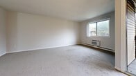 Located on Generation Blvd in Toronto, Ontario, this 2-bedroom, 1-bathroom residence offers a practical and well-organized layout across its floor plan. The spacious living room is a central highlight, featuring soft wall-to-wall carpeting, a ceiling fan, a wall-mounted air conditioning unit, and large windows that invite natural light. Sliding glass doors lead to a private balcony, extending the living space outdoors. The kitchen is accessed directly from the living area and is outfitted with white cabinetry, tile flooring, and standard appliances including an electric range and refrigerator. The primary bedroom is generously sized, featuring wide sliding closet doors, carpet flooring, and large windows overlooking the surroundings. The second bedroom is similarly carpeted and bright, with a sliding door providing balcony access. Both bedrooms are connected via hallways that facilitate smooth circulation throughout the unit. The full bathroom includes a tiled tub-shower surround, toilet, and vanity mirror. Neutral tones and clean finishes throughout lend the space a calm, understated ambiance. Baseboard heating is present in the main living areas, ensuring year-round comfort in this Toronto residence.