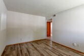 Located at 7671 N Garfield Ave in Gladstone, Missouri, this single-floor home offers a straightforward and functional layout suited for comfortable everyday living. The entryway features a warm wood-tone door with a decorative porthole window, welcoming residents into a space finished with durable wood-look flooring that extends through the main living areas and hallways.

The living area is generously sized with neutral white walls, wood-toned baseboards, and built-in ventilation grilles, creating a clean and practical environment. A hallway connects the primary spaces, providing access to the bedrooms, bathroom, and a closet with shelving.

The bedrooms are carpeted for added comfort and each features windows with blinds that allow natural light while maintaining privacy. The kitchen is equipped with warm wood cabinetry, a double stainless steel sink, a freestanding electric range, and a white tile backsplash. A window above the sink brings in natural light and outdoor views.

The bathroom includes a full tub and shower combination with white surround, a toilet, and classic mosaic tile flooring, maintaining a clean and functional aesthetic throughout. Overall, this home presents a practical and well-maintained single-level living space in a residential Gladstone neighborhood.