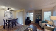 Located at 18081 Midway Rd in Dallas, Texas, this single-floor residence offers a thoughtfully arranged layout with distinct living, dining, kitchen, bedroom, and bathroom areas. The living room is a welcoming focal point, featuring rich hardwood-style flooring, multiple windows with slatted blinds that allow ample natural light, and a textured ceiling. The space comfortably accommodates a seating area and flows seamlessly into the dining room, which includes a built-in shelving unit, a ceiling fan, and vertical blinds providing access to an adjacent area. The galley-style kitchen is efficiently designed with granite-look countertops, warm wood cabinetry, a double sink, and black appliances. A dedicated laundry alcove off the kitchen houses a side-by-side washer and dryer. The bedrooms are carpeted and each features a ceiling fan and windows with natural light. The bathroom includes a tub-shower combination with a curved rod, granite-look vanity countertop, and wood-toned cabinetry. Throughout the residence, neutral wall tones and consistent finishes create a cohesive and comfortable ambiance suited for everyday living in North Dallas.