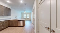 This thoughtfully designed single-floor residence offers a cohesive and functional layout with 1 bedroom and 1 bathroom. Light-toned hardwood-style flooring flows seamlessly throughout the entire space, contributing to a clean, modern aesthetic. The kitchen is a standout feature, equipped with rich warm-toned cabinetry, granite-style countertops, and a full suite of stainless steel appliances including a refrigerator, range, built-in microwave, and dishwasher. A kitchen island with a sink adds to the workspace and serves as a natural divider between the kitchen and the open living area. The living area is bright and airy, benefiting from a ceiling fan and a pair of windows that invite natural light and views of the outdoors. The bedroom is a comfortable, well-proportioned space featuring a ceiling fan, a window with blinds, and direct access to the hallway. The bathroom is finished with a granite-top vanity, warm wood cabinetry, and a tiled shower. A built-in closet with multi-level shelving is conveniently located adjacent to the bathroom, offering practical storage. Neutral wall tones and clean white trim unify the space, creating a bright and inviting atmosphere throughout.
