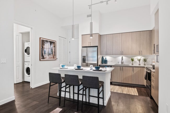 Kitchen with oak cabinetry, undercabinet lighting, white quartz countertops, and hard-surface vinyl plank flooring - Avalon Fort Lauderdale
