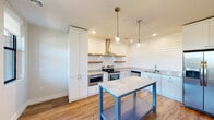 This well-appointed single-floor residence offers a smart and efficient layout across one bedroom, one bathroom, a kitchen, and a dedicated closet. The standout feature of the home is the kitchen, which showcases striking shiplap wall paneling, crisp white cabinetry, and granite-style countertops. A stainless steel appliance suite — including a gas range with a sleek wall-mounted hood, double oven, side-by-side refrigerator, and dishwasher — is complemented by open wood floating shelves and pendant lighting over a freestanding island with additional storage below. Warm hardwood-style flooring runs throughout the main living areas, adding a cohesive, contemporary feel. The bedroom is carpeted for comfort and features a ceiling fan and a large window framing outdoor views and abundant natural light. It connects conveniently to the walk-in closet, which is outfitted with wrap-around shelving and hanging rods, and to the full bathroom. The bathroom is finished with classic subway tile surrounding the tub and shower, a patterned penny-tile floor, a granite-topped vanity, and white cabinetry. The living area also features a ceiling fan, multiple windows, and a glass-panel entry door that enhances the open, airy character of the space.