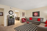 This single-floor, two-bedroom, one-bathroom unit offers a practical and well-organized layout across a comfortable footprint. The living room serves as the central gathering space, featuring carpet flooring, a textured ceiling, and a front-facing window that brings in natural light. A hallway connects the main living area to the rest of the unit.

The combined kitchen and dining area is a functional space with white cabinetry, granite-style countertops, a black appliance suite including a dishwasher and refrigerator, and tile flooring. A window above the sink provides additional natural light. A stacked washer and dryer unit is conveniently integrated into this space alongside a dining area with room for a full table and seating.

The primary bedroom is a well-proportioned room with carpet flooring, a ceiling fan, and a window offering natural light. The second bedroom is similarly appointed with carpet, a ceiling fan, and a window. Both rooms provide adequate space for standard bedroom furnishings.

The full bathroom includes tile flooring, a tub/shower combination with white tile surround, a vanity with granite-style countertops, and white cabinetry. A hallway connects all rooms, completing this efficiently designed single-level unit.