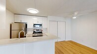 Located at 140 S Van Dorn Street in Alexandria, Virginia, this two-bedroom, two-bathroom residence offers a well-organized single-floor layout with a clean, modern aesthetic throughout. Light wood flooring runs continuously across the living spaces, complementing the bright white walls and lending a cohesive, airy feel to the interior.

The combined kitchen and living area serves as the heart of the home. The kitchen features white cabinetry, a subway tile backsplash, stainless steel appliances including a gas range and refrigerator, and a light-toned countertop peninsula that provides both prep space and a casual dining option. The adjacent living area is open and bright, with sliding glass doors that lead directly to a private balcony overlooking the landscaped grounds and tree-lined surroundings below.

Both bedrooms are well-proportioned, with the primary bedroom offering generous square footage, a large sliding-door closet, and a window that brings in natural light. The second bedroom similarly features a window and ample space. Across the residence, five closets provide exceptional storage, including a walk-in closet. The two bathrooms are finished in clean white tones, each featuring a tub-shower combination. A central hallway connects the rooms efficiently, completing this thoughtfully laid-out Alexandria residence.