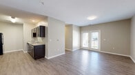 Located at 5700 Bruns Dr in Louisville, Kentucky, this single-story home offers three bedrooms, two bathrooms, and a practical, efficiently designed floor plan. The living room greets you with warm wood-look luxury vinyl plank flooring, neutral walls, and a set of glass-paned French doors that invite natural light and provide outdoor access. The galley-style kitchen is a standout feature, equipped with dark espresso cabinetry, light granite-style countertops, a full suite of black appliances including a refrigerator, range, microwave, and dishwasher, and a stainless steel sink — all set atop matching LVP flooring. The three bedrooms offer plush carpeting, ceiling fans, and double-door closets providing ample storage. The primary bedroom is a comfortable retreat with its own generous closet space. Both bathrooms are finished with dark vanity cabinetry, granite-style countertops, tile-look flooring, and tub-shower combinations with clean white surrounds. Neutral-toned walls and white trim flow consistently throughout the home, creating a cohesive and move-in-ready aesthetic. A central hallway connects the living spaces efficiently, and a dedicated closet adds additional storage convenience.