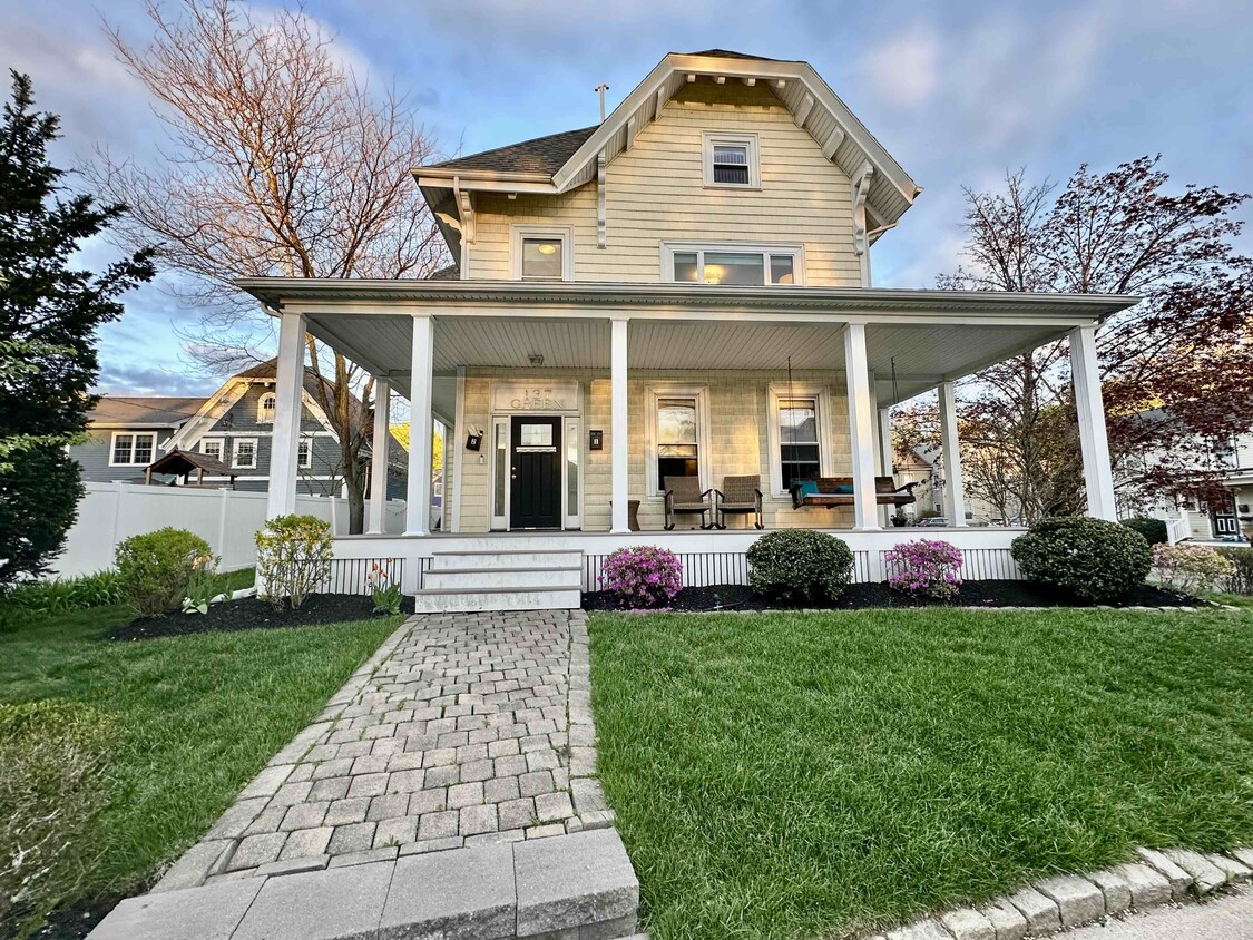 Charming Melrose home with welcoming front porch, landscaped yard, and warm evening curb appeal. - 137 Green St (Melrose, MA)