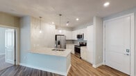 This single-floor residence showcases a thoughtfully designed open layout with modern finishes throughout. The kitchen serves as a central highlight, featuring crisp white shaker cabinetry, gray subway tile backsplash, and light granite countertops. A peninsula with an undermount sink and pendant lighting provides additional workspace and casual seating. Stainless steel appliances, including a side-by-side refrigerator with ice maker, electric range, and built-in microwave, complete the well-appointed kitchen. Wood-look flooring flows through the main living and kitchen areas, adding warmth to the contemporary aesthetic.

The bedrooms are generously sized, finished with neutral carpet, ceiling fans with lighting, and windows fitted with white blinds that allow natural light while maintaining privacy. Each bedroom includes closet space, with at least one walk-in closet equipped with wire shelving systems for organized storage.

The bathrooms are finished with white cabinetry, granite-topped vanities, and large framed mirrors with overhead lighting. A tub-shower combination and tile flooring complete the secondary bath, while the primary bath features a spacious vanity. Neutral gray walls and white trim carry throughout, contributing to a clean, cohesive, and move-in-ready atmosphere.