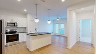 Located at 510 Cedar Tree Rd in Wellford, SC, this thoughtfully designed one-bedroom, one-bathroom residence offers a clean, contemporary aesthetic throughout its single-floor layout. The open-concept living and kitchen area serves as the heart of the home, where light hardwood-style flooring flows seamlessly underfoot. The kitchen is outfitted with crisp white cabinetry, a hexagonal tile backsplash, stainless steel appliances including a refrigerator, range, and microwave, and a central island with a dark countertop and undermount sink. Dual globe pendant lights hang above the island, adding a modern, decorative touch. The living area extends naturally from the kitchen, bathed in natural light from French doors that open to the outdoors, and is complemented by a ceiling fan overhead. A hallway leads to the private bedroom, which features plush carpeting, a ceiling fan, and a window with blinds that invite natural light. An adjacent closet provides dedicated storage. The bathroom continues the home's modern palette with white cabinetry, a dark countertop, an undermount sink, and wood-style flooring. Outside, a fenced side yard with turf offers a private outdoor area. The overall ambiance is bright, clean, and move-in ready.