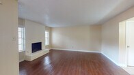 This two-floor home offers a well-organized layout with a variety of functional spaces across both levels. The living room serves as the centerpiece of the main floor, featuring rich hardwood flooring that extends throughout, warm neutral-toned walls, and a textured ceiling. A brick-surround fireplace with a raised hearth anchors one wall, adding a classic focal point to the space. Natural light filters in through a window nearby, enhancing the open, airy feel of the room.

The kitchen is equipped with dark espresso-toned cabinetry, light countertops, tile flooring, and a stainless steel refrigerator. The galley-style layout provides efficient use of space with ample storage on both sides.

The bathrooms feature dark-framed mirrors, light countertop vanities with dark cabinetry below, and well-lit fixtures. One bathroom includes a glass-enclosed tiled shower stall with built-in shelving.

The bedrooms are carpeted for comfort and include ceiling fans with lighting and natural light from windows. At least one bedroom features access to a dedicated walk-in closet, offering generous storage capacity. Throughout the home, a consistent neutral color palette and textured ceilings create a cohesive, understated ambiance.