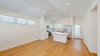 Located in Weatherford, TX, this thoughtfully designed single-story home offers a bright, modern aesthetic with clean lines and high-quality finishes throughout. The open-concept living and kitchen area serves as the heart of the home, showcasing soaring vaulted ceilings, recessed lighting, and warm-toned luxury vinyl plank flooring that extends throughout the space. Large windows invite abundant natural light, enhancing the airy, welcoming atmosphere.

The kitchen is a standout feature, equipped with crisp white shaker cabinetry, a white quartz-topped center island, subway tile backsplash, and a full suite of stainless steel appliances including a French door refrigerator, range, microwave, and dishwasher. The adjacent living area offers a versatile layout with a glass-paneled entry door providing additional light.

The spacious primary bedroom includes a ceiling fan, a generous window with natural light, and access to a well-appointed en suite bathroom featuring a glass-enclosed walk-in shower with elegant marble-style tile, plus a dedicated walk-in closet. Two additional bathrooms feature white vanities with undermount sinks and mirrored medicine cabinets. The home also includes two hallways and a dedicated closet, offering practical storage and smooth circulation throughout.