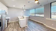 Located at 1230 Elm St in Manchester, NH, this well-appointed 2-bedroom, 2-bathroom unit offers a thoughtfully designed layout across a single floor. The open-concept kitchen is a standout feature, showcasing white shaker cabinetry, quartz countertops, stainless steel appliances, and a peninsula with a matte black sink faucet and pendant lighting overhead. A tiled herringbone fireplace anchors the living area, adding warmth and character, while large floor-to-ceiling windows flood the space with natural light and provide views of the surrounding area. Wood-look plank flooring runs throughout the main living areas, complementing the contemporary aesthetic. Both bathrooms are finished with quartz vanity tops, white cabinetry, and matte black fixtures, with one bathroom featuring a full tub-shower combination and wood-look tile flooring. The bedrooms are carpeted with patterned tile-style carpet, offering a comfortable feel underfoot. The spacious primary bedroom includes a built-in closet with a wire rack system. A stacked in-unit washer and dryer provides added convenience. The unit's neutral gray palette and modern hardware selections create a clean, cohesive look throughout.
