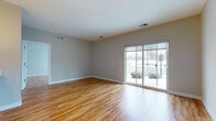 Located at 38601 Mentor Ave in Willoughby, Ohio, this single-floor unit offers a thoughtfully designed layout with consistent warm-toned hardwood flooring throughout. The open living area is a standout feature, anchored by a large sliding glass door that floods the space with natural light and provides direct access to the outdoors. Neutral gray walls complement the flooring, creating a clean, modern aesthetic.

The kitchen is well-equipped with gray shaker-style cabinetry, white quartz countertops, a subway tile backsplash, stainless steel appliances including a range, microwave, refrigerator, and dishwasher, and a deep undermount sink with a contemporary faucet. Pendant lighting adds a refined touch overhead.

The unit includes two bathrooms. The primary bathroom features a glass-enclosed walk-in shower with floor-to-ceiling tile surround and a rain showerhead, paired with a gray vanity and white countertop. The second bathroom offers a full tub-shower combination with a matching gray vanity. A dedicated laundry area with side-by-side washer and dryer and an electrical panel provides added convenience. Bedroom spaces are well-proportioned with ample natural light from large windows.