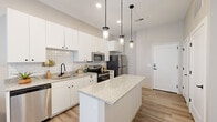 Located at 4540 Swan Ave in St. Louis, MO, this single-floor residence offers a clean, contemporary design throughout. The kitchen serves as a central highlight, featuring crisp white cabinetry with matte black hardware, a classic subway tile backsplash, granite countertops, and a generous center island ideal for meal prep or casual dining. Stainless steel appliances — including a refrigerator, electric range, and over-the-range microwave — complete the well-appointed cooking space. Stylish pendant lighting hangs above the island, adding a modern touch. Light wood-style flooring runs throughout, creating a cohesive and airy feel that extends seamlessly from the kitchen into the open living area, which benefits from natural light streaming through large windows. The bedrooms are comfortably scaled, each with windows that invite natural light and offer views of greenery outside. The bathroom is thoughtfully designed with a wide granite-topped vanity, white cabinetry, matte black fixtures, and a large LED-backlit mirror that enhances both functionality and ambiance. Throughout the space, the neutral color palette and modern finishes work together to create a bright, welcoming atmosphere that is both practical and stylish.