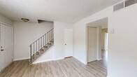 Located at 893 Briar Creek Court NE in Conyers, GA, this two-story home offers a practical and well-organized layout spread across two floors. The main level features a bright, open living area with light-toned vinyl plank flooring, crisp white walls, and a textured ceiling that carries throughout much of the home. A staircase with a dark metal baluster railing connects both floors, serving as a functional architectural focal point. The galley-style kitchen is equipped with rich dark wood cabinetry, granite-look countertops, a double stainless steel sink, and black appliances, offering ample storage and counter space. The two full bathrooms are finished consistently, each featuring dark vanity cabinets with stone-look counters, a single sink, and tiled tub-shower combinations with clean white surrounds. Upstairs, the three bedrooms are carpeted and filled with natural light from windows with views of surrounding greenery. The generously sized primary bedroom includes a double closet, while the home's seven total closets ensure abundant storage throughout. Utility rooms on each floor add further convenience. The overall aesthetic is clean, neutral, and move-in ready.
