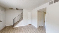 Located at 893 Briar Creek Court NE in Conyers, GA, this two-story home offers a practical and well-organized layout spread across two floors. The main level features a bright, open living area with light-toned vinyl plank flooring, crisp white walls, and a textured ceiling that carries throughout much of the home. A staircase with a dark metal baluster railing connects both floors, serving as a functional architectural focal point. The galley-style kitchen is equipped with rich dark wood cabinetry, granite-look countertops, a double stainless steel sink, and black appliances, offering ample storage and counter space. The two full bathrooms are finished consistently, each featuring dark vanity cabinets with stone-look counters, a single sink, and tiled tub-shower combinations with clean white surrounds. Upstairs, the three bedrooms are carpeted and filled with natural light from windows with views of surrounding greenery. The generously sized primary bedroom includes a double closet, while the home's seven total closets ensure abundant storage throughout. Utility rooms on each floor add further convenience. The overall aesthetic is clean, neutral, and move-in ready.