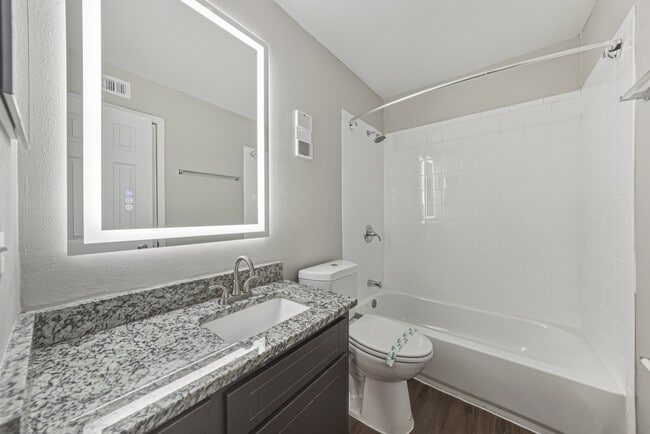 Modern bathroom with granite vanity and bathtub shower combination - Magnolia Apartments