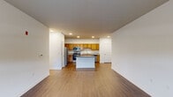 This single-floor residence is designed with an open-concept layout that seamlessly connects the living area and kitchen, creating a spacious, cohesive environment. The kitchen is well-appointed with warm-toned wood cabinetry, granite countertops, and a full suite of stainless steel appliances, including a refrigerator, electric range, built-in microwave, and dishwasher. A central island with a granite surface provides additional workspace and a natural focal point for the area. Wood-style flooring runs throughout the main living spaces, contributing to a clean, uniform aesthetic.

The living area benefits from natural light through a window overlooking the surrounding outdoors, while crisp white walls and recessed lighting maintain a bright, neutral atmosphere throughout. Bedroom spaces feature plush carpeting for added comfort, with at least one room offering access to a walk-in closet with built-in shelving for organized storage.

Two bathrooms serve the unit, each consistent in finish with wood cabinetry and granite countertops. One bathroom features a glass-enclosed walk-in shower, while the second offers a tub-shower combination with tiled surroundings and a curved curtain rod. Wood-style flooring ties both bathrooms together with the rest of the unit's design.