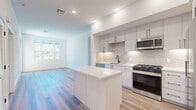 Located at 1205 Aviara Parkway in Carlsbad, CA, this thoughtfully designed 2-bedroom, 2-bathroom residence offers a clean, modern aesthetic throughout. The open-concept kitchen and living area serves as the heart of the home, showcasing white and light gray cabinetry with matte black hardware, a subway tile backsplash, quartz countertops, a central kitchen island, and a full suite of stainless steel appliances. Light wood-tone flooring runs seamlessly throughout the space, enhancing the bright, airy feel. The living area benefits from large windows and a glass door that invite abundant natural light and provide views of the surrounding greenery.

Both bedrooms are well-proportioned with white walls, wood-tone flooring, and windows framing pleasant outdoor views. The primary bedroom includes a spacious walk-in closet outfitted with dual hanging rods and shelving. A second closet provides additional storage. The two bathrooms continue the home's modern palette — one features a walk-in shower with frameless glass and dark fixtures, while the second offers a full soaking tub with shower, white tile surround, and matching matte black hardware. A hallway connects the rooms efficiently, completing this well-appointed Carlsbad residence.