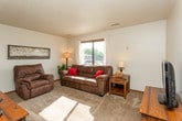 This single-floor residential unit offers a comfortable and practical layout designed for everyday living. The kitchen is a functional highlight, featuring dark taupe cabinetry, light stone-look countertops, and a full suite of stainless steel appliances including an electric range with microwave above, a dishwasher, and a refrigerator. Durable wood-look flooring runs through the kitchen and dining area, where a compact dining set provides a cozy spot for meals.

The living room is generously sized and filled with natural light from a large picture window. Plush carpeting and neutral wall tones create a warm, inviting atmosphere, with ample room for comfortable seating arrangements.

The unit includes multiple bedrooms, each carpeted and finished with clean, neutral walls and sliding or hinged closet storage. Windows in several bedrooms allow for natural light and outdoor views of the surrounding landscape. Each room offers a peaceful, restful environment.

The bathroom features a wide vanity with warm wood cabinetry, a light countertop, a mirrored medicine cabinet with Hollywood-style lighting above, and wood-look flooring that ties cohesively to the rest of the unit.

Throughout the space, textured ceilings, wood trim baseboards, and consistent neutral tones create a unified, understated aesthetic that is both livable and well-maintained.