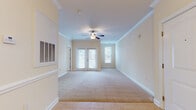 Located at 114 Avalon Park Rd in Mooresville, NC, this single-floor residence offers a thoughtfully designed layout with consistent finishes throughout. The main living area is spacious and bright, featuring plush wall-to-wall carpeting, crown molding, and a ceiling fan with light fixture. French doors invite natural light while providing access to the outdoors, complemented by additional windows fitted with white blinds. An adjoining area, accented by a chandelier and chair-rail molding, adds a refined dining or flex space.

The kitchen is well-equipped, showcasing rich cherry wood cabinetry, granite countertops, and tile flooring. Black appliances — including an electric range, built-in microwave, and dishwasher — provide a sleek, functional contrast to the warm cabinetry tones.

The bedrooms continue the carpeted, neutral aesthetic, each offering ample natural light through blinds-covered windows. One bedroom features a spacious walk-in closet with built-in shelving, while another includes direct access to additional rooms. The bathroom is clean and functional, with a granite-topped vanity with wood cabinetry, a tub-shower combination, and tile flooring, all finished with brushed nickel hardware. Throughout the home, warm neutral tones and consistent finishes create a cohesive and welcoming atmosphere.